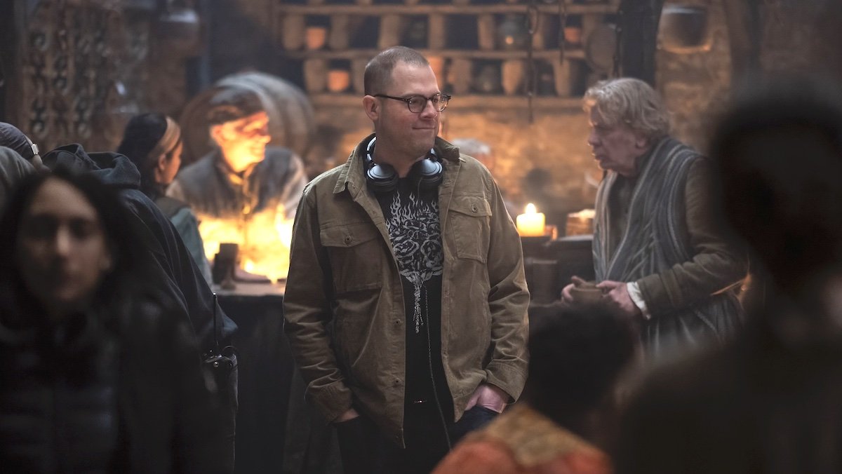 Showruner Ryan Condal in glasses and a coat on the set of a tavern from House of the Dragon