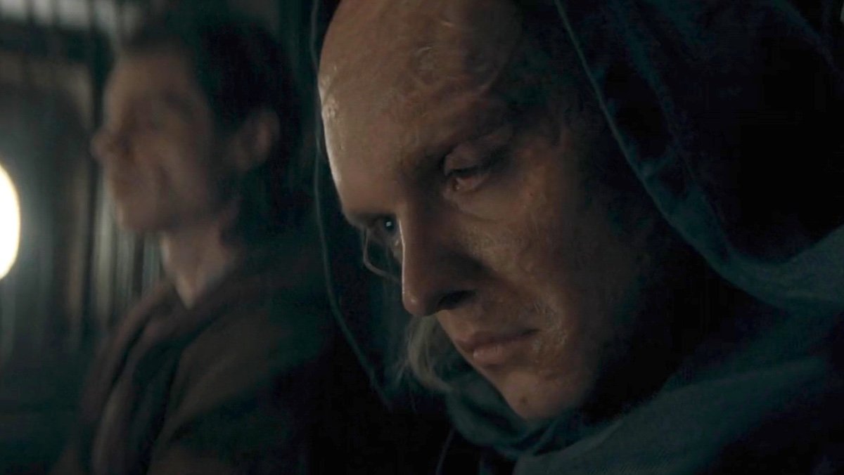 A scarred sad Aegon with a hood on sits nears Larys on House of the Dragon