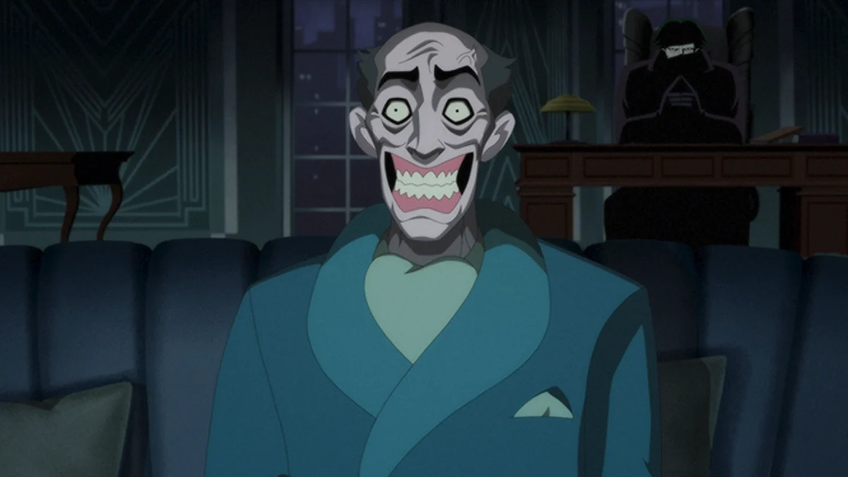 Still from the Batman: Caped Crusader show featuring Joker sitting behind a man.